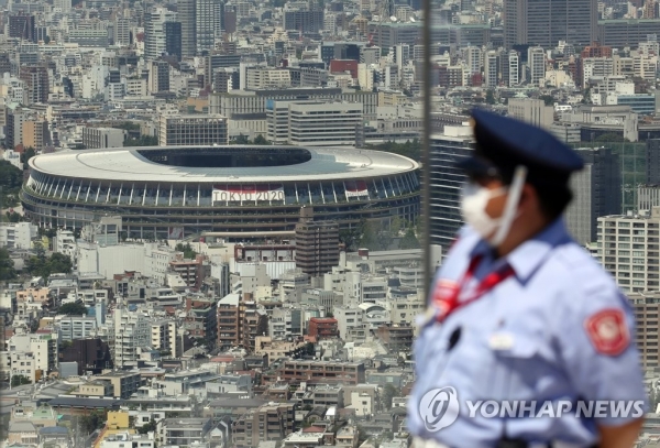 도쿄올림픽 개막식을 앞둔 21일 일본 도쿄도이 한 고층 건물 전망대에서 경비원이 근무 중이다. 뒤쪽이 개최식이 열리는 일본 국립경기장. [사진=연합뉴스]