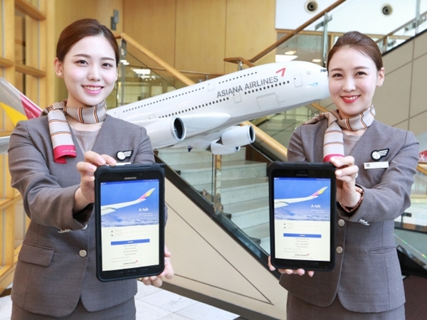 아시아나항공 승무원들이 스마트워크플랫폼인 ‘에이탭(A-tab)’을 들어보이고 있다. [사진=아시아나항공 제공]