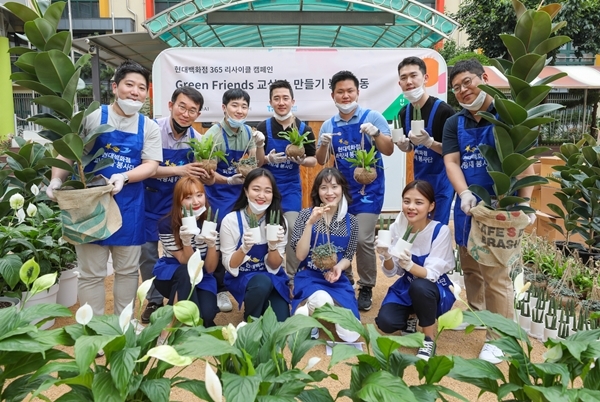 지난 18일 오후 서울 구로구 매봉초등학교에서 현대백화점 직원들이 공기정화식물과 함께 기념 촬영을 하고 있다. [사진=현대백화점 제공]