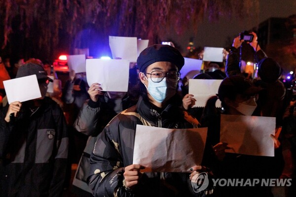 27일 중국 베이징에서 열린 우루무치 화재 희생자 추도식에서 코로나19 봉쇄 조치에 반대하는 시민들이 검열에 대한 저항의 상징으로 '백지 시위'를 펼치고 있다. [사진=로이터/연합뉴스]