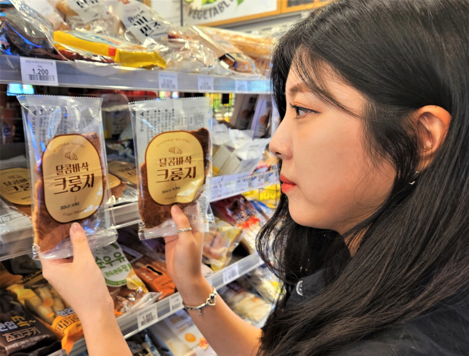서울 성동구에 위치한 이마트24 매장에서 고객이 '달콤바삭 크룽지' 상품을 살펴보고 있다. [사진=이마트24 제공]